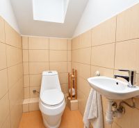 Badezimmer im Einfamilienhaus mit Toilette und Waschbecken, beige Fliesen.