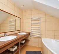 Ein Badezimmer mit Doppelwaschbecken, Spiegel und Badewanne im Dachgeschoss eines Einfamilienhauses.