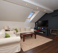 Wohnzimmer in einem Einfamilienhaus mit Kamin, Sofas und Holzboden.