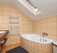 Ein Badezimmer im Dachgeschoss mit Badewanne, Doppelwaschbecken und Dachfenster in einem Einfamilienhaus.