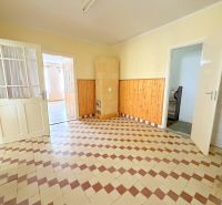 Ein Raum in einem Einfamilienhaus mit Fliesenboden und Holzverkleidung an den Wänden.