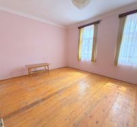Ein Raum eines Einfamilienhauses mit einem Holzboden, einem Tisch und Vorhängen.