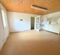 Das Innere eines Einfamilienhauses mit Holzbalkendecke, alten Möbeln und weißen Wänden.