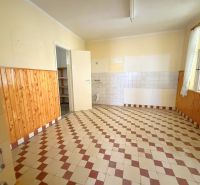 Küche in einem Einfamilienhaus mit Fliesenboden und Holzverkleidung an den Wänden.