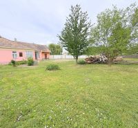 Ein Einfamilienhaus in Dunakiliti mit rosa Fassade, umgeben von einem großzügigen Garten und Bäumen.
