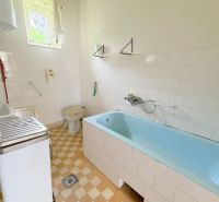 Badezimmer mit Badewanne und Fliesen in einem Einfamilienhaus mit einfacher Ausstattung.