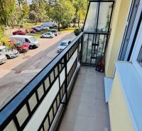Ein Balkon mit Blick auf Bäume und Autos in der Nádražná-Straße in Partizánske, der Raum einer 3-Zimmer-Wohnung.