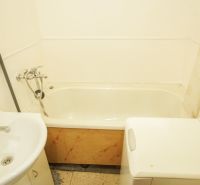 Badezimmer in einer 2-Zimmer-Wohnung mit Badewanne, Waschbecken und Waschmaschine.