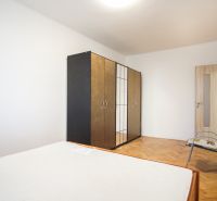 Schlafzimmer mit Kleiderschrank, Bett und Boden mit Holzdekor in einer 2-Zimmer-Wohnung.