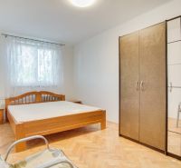 Schlafzimmer in einer Zweizimmerwohnung mit Holzboden, Bett und Schrank.