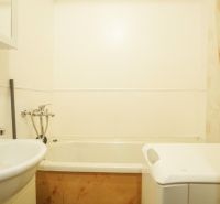 Badezimmer in einer 2-Zimmer-Wohnung mit Waschbecken, Badewanne und Waschmaschine.