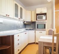 Küche in einer 2-Zimmer-Wohnung mit weißen Schränken und einem Esstisch.