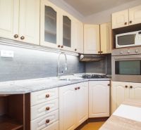 Küche in einer 2-Zimmer-Wohnung mit weißen Schränken und eingebauten Geräten.