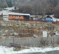 Ein verschneites Grundstück mit einem Einfamilienhaus in Oščadnica, umgeben von Grünflächen und Holzstrukturen.
