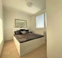 Schlafzimmer mit großem Bett, Spiegel und Fenstern in einer 3-Zimmer-Wohnung.