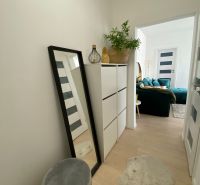 Flur mit weißen Möbeln, Spiegel und Dekorationsgegenständen in einer 3-Zimmer-Wohnung.