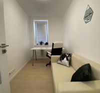 Ein enger Arbeitsbereich in einer 3-Zimmer-Wohnung mit einem Tisch, einem Stuhl und einem Sofa.