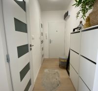 Der Flur einer 3-Zimmer-Wohnung mit weißen Möbeln und Holzboden.