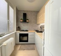 Küche in einer 3-Zimmer-Wohnung mit weißen Schränken, einem Gasherd und einem Heizkörper.
