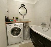 Badezimmer einer 3-Zimmer-Wohnung mit Waschmaschine, Badewanne, Waschbecken und rundem Spiegel.