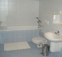 Badezimmer in einer 3-Zimmer-Wohnung mit Badewanne, Waschbecken und Toilette, blau-weiße Fliesen.