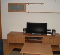 Wohnzimmer in einer 3-Zimmer-Wohnung mit Holzboden, Fernseher und Möbeln.