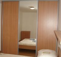 Schlafzimmer in einer 3-Zimmer-Wohnung mit einem großen Einbauschrank und einem Boden mit Holzdekor.