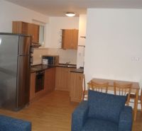 Küche in einer 3-Zimmer-Wohnung mit Küchenzeile, Esstisch und Boden mit Holzdekor.