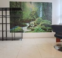 Innenraum von Geschäftsräumen mit Regal, Sessel und Naturmotiv an der Wand.
