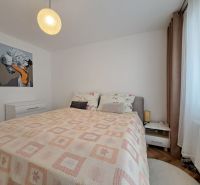 Schlafzimmer mit hellem Bett und Nachttischen in einer 3-Zimmer-Wohnung mit Wanddekoration.