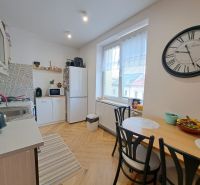 Küche in einer 3-Zimmer-Wohnung mit Holzboden, Esstisch und großer Uhr.