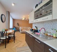 Küche mit Essecke in einer 3-Zimmer-Wohnung, Boden mit Holzdekor, Sofa.