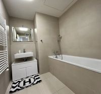 Badezimmer in einer 2-Zimmer-Wohnung mit Badewanne, Waschbecken und Wandspiegel.