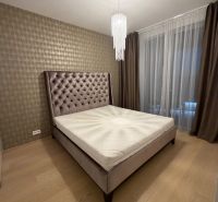 Schlafzimmer in einer 2-Zimmer-Wohnung mit Bett, Vorhängen und Boden in Holzoptik.