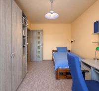 Ein Zimmer in einer 3-Zimmer-Wohnung mit einem Bett, einem Schrank, einem Tisch und einem blauen Sessel.