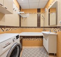 Badezimmer in einer 3-Zimmer-Wohnung mit Fliesen in warmen Farbtönen und einer Bosch-Waschmaschine.