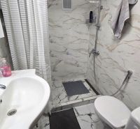 Badezimmer in einem Einfamilienhaus mit Waschbecken, Dusche und Fliesen mit Marmordekor.