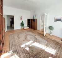 Ein helles Wohnzimmer mit Holzboden, Teppich und Möbeln in einer Zweizimmerwohnung.