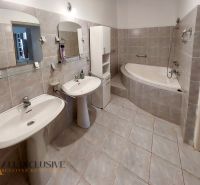 Badezimmer mit zwei Waschbecken, Eckbadewanne und hellen Fliesen in einer 2-Zimmer-Wohnung.