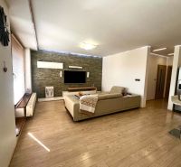 Wohnzimmer in einer 3-Zimmer-Wohnung mit Holzboden, Fernseher und Sofa.