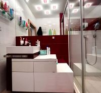 Badezimmer mit Dusche, Waschbecken und Regalen in einer 3-Zimmer-Wohnung.