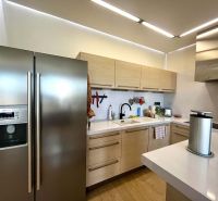 Küche in einer 3-Zimmer-Wohnung mit Holzboden, weißer Küchenzeile und Edelstahlgeräten.