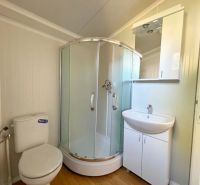 Badezimmer mit Dusche, Waschbecken und Boden mit Holzdekor. Besondere Immobilien.