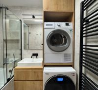 Badezimmer in einer 3-Zimmer-Wohnung mit Waschmaschine und Trockner, helle Fliesen, Holzelemente.