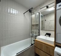 Modernes Badezimmer in einer 3-Zimmer-Wohnung mit Badewanne, Waschbecken und Waschmaschine.