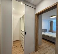 Flur mit Schiebetüren und Bett, Boden mit Holzdekor in einer 3-Zimmer-Wohnung.