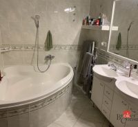 Badezimmer mit Eckbadewanne, Doppelwaschbecken und Keramikfliesen in einer 3-Zimmer-Wohnung.
