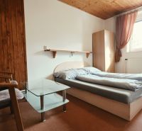 Schlafzimmer der Ferienwohnung mit Doppelbett, Sesseln und Fenster, Boden mit Holzdekor.
