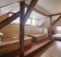 Dachzimmer in einer Ferienwohnung mit Holzboden und Betten.