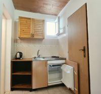 Küchenzeile im Ferienapartment mit Holzschränken, Spüle und Minikühlschrank.